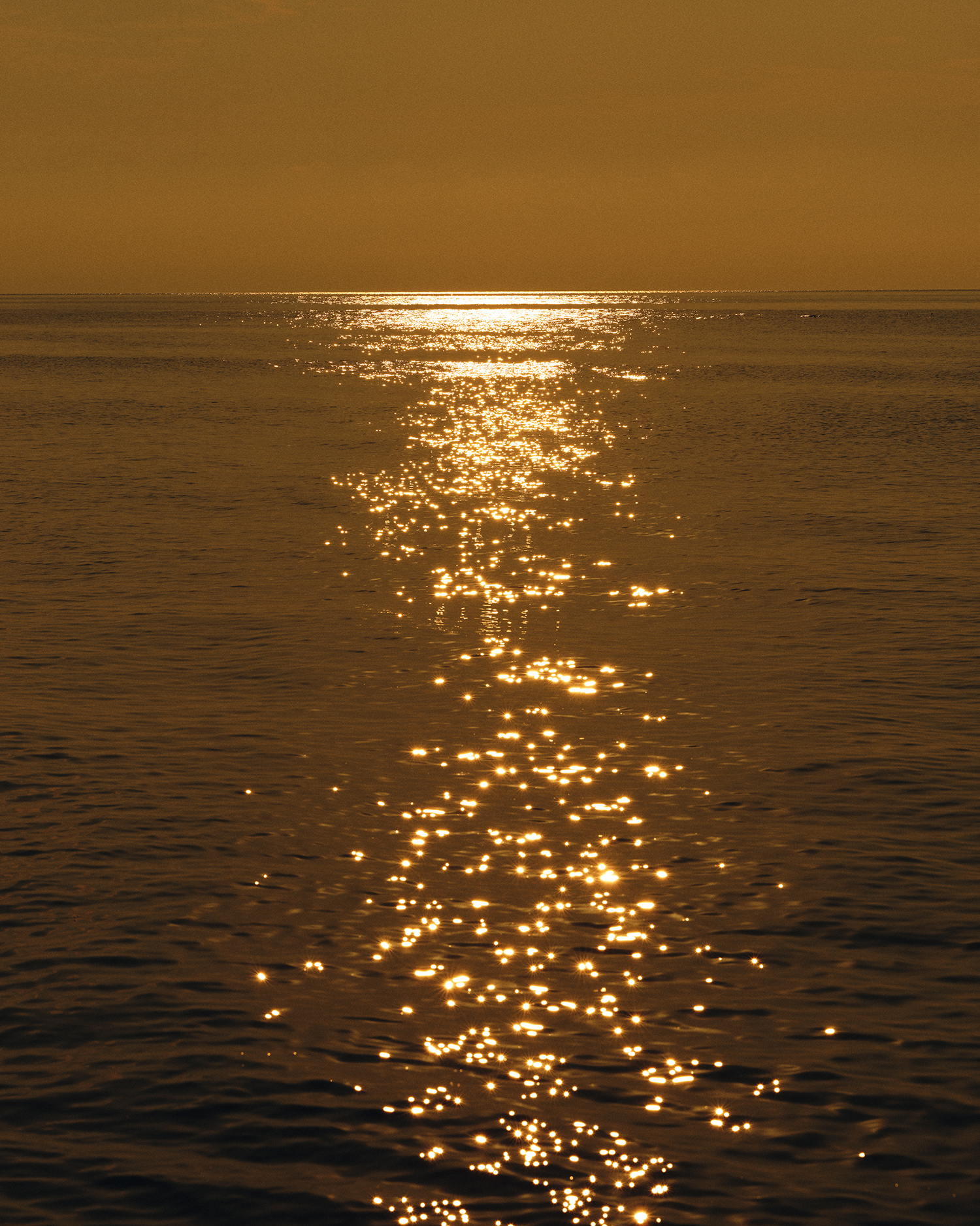 Sun rays shining on lake water with a hazy yellow sky