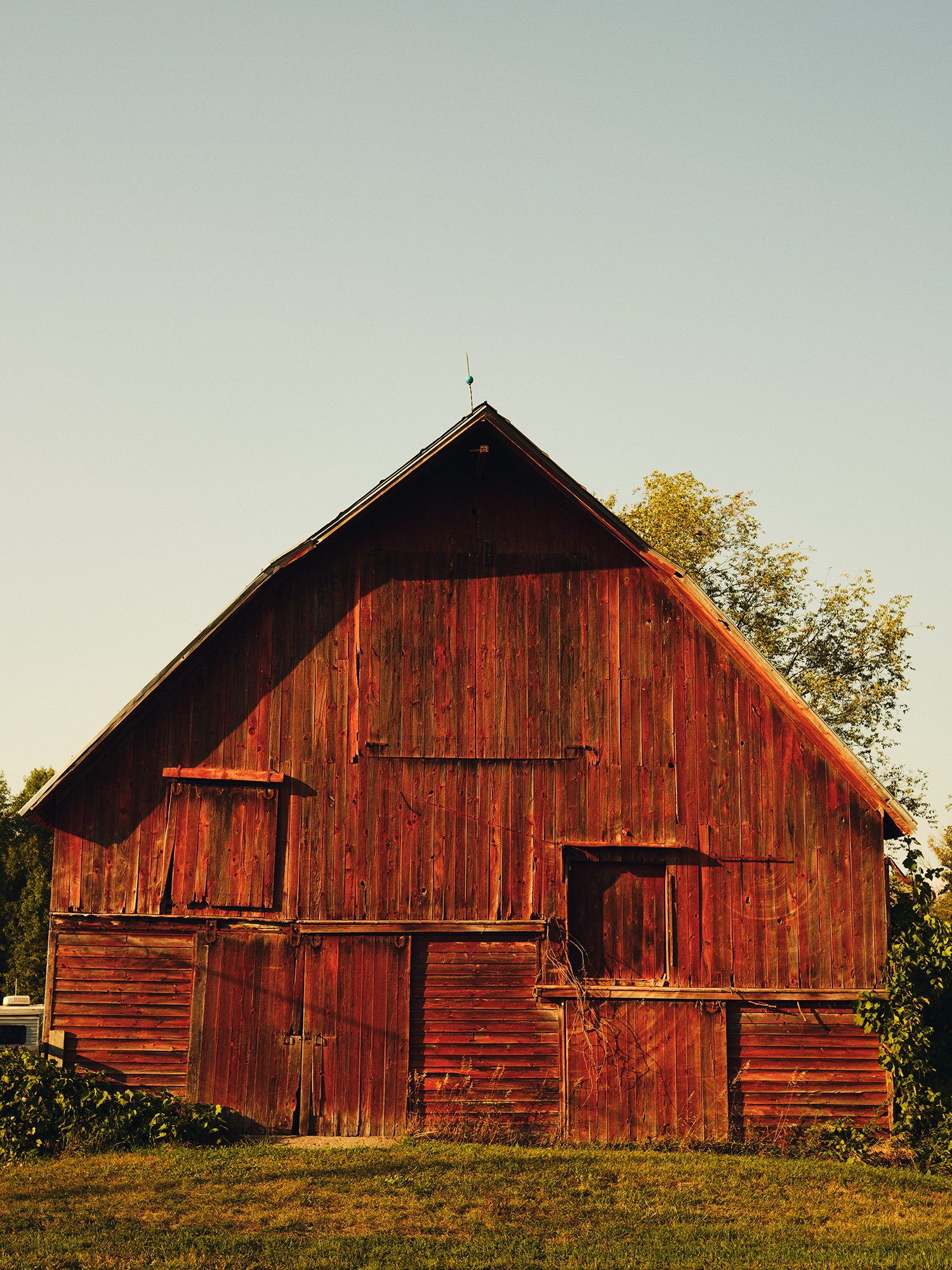 A rustic red barn with the sun shining on it