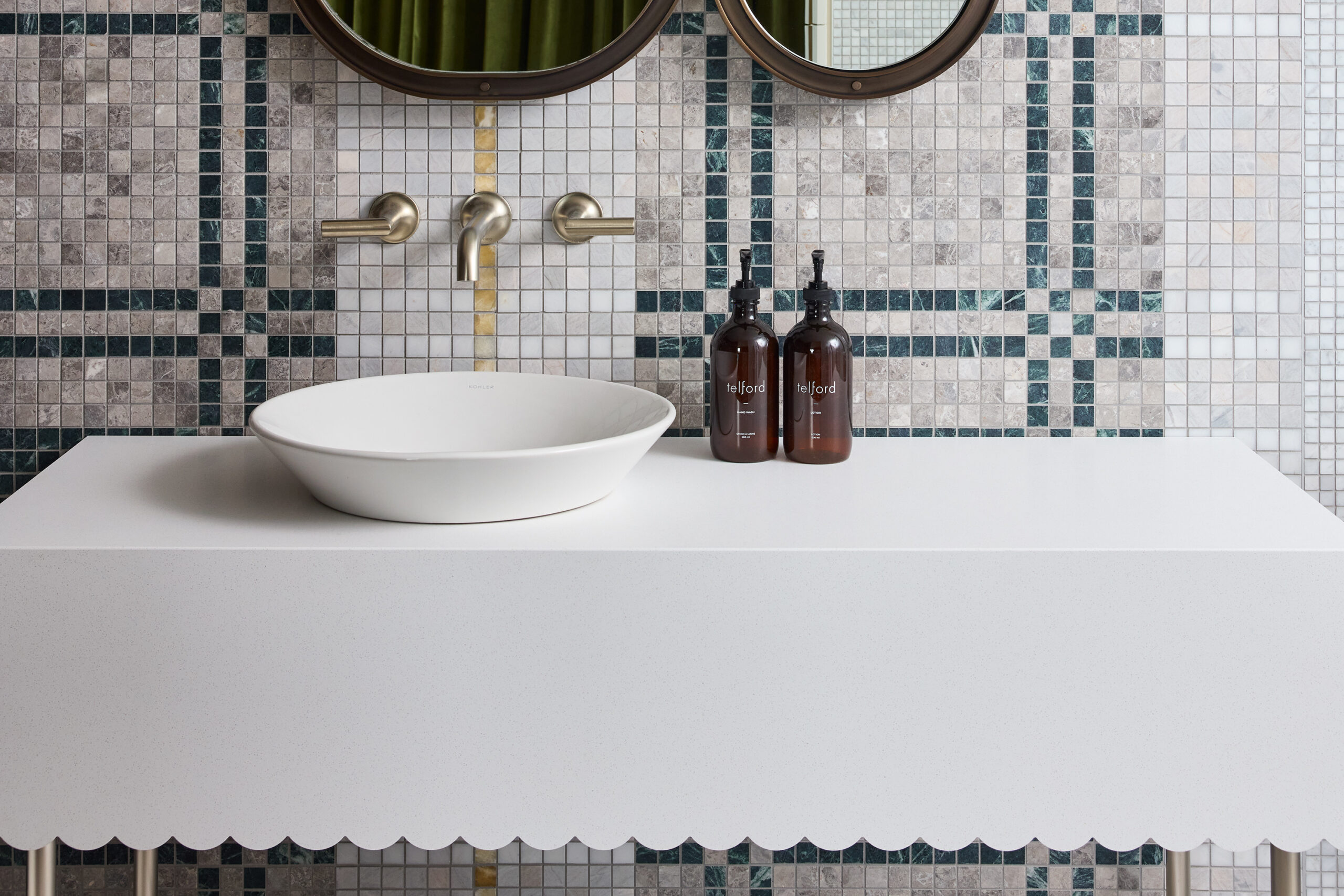 White bowl sink with gold fixtures on a green, grey and white tiles wall